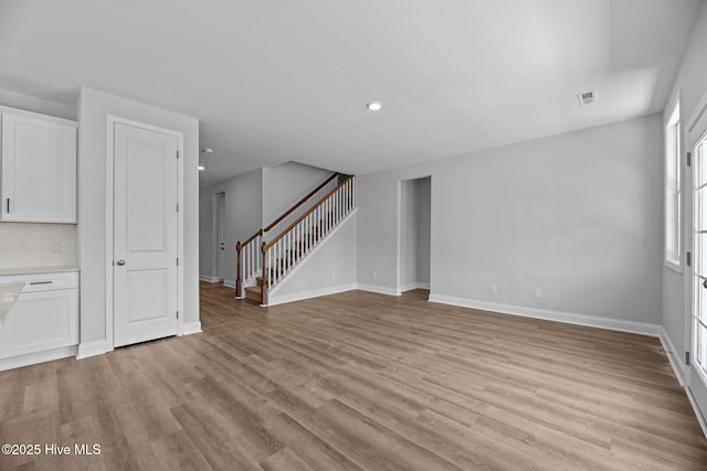 1007 Tawney Trce, New Bern, NC 28562 - unfurnished living room with light wood-style flooring, stairs, baseboards, and recessed lighting