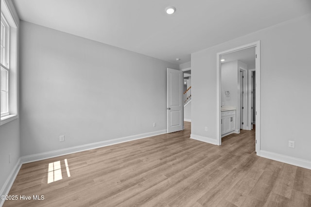1007 Tawney Trce, New Bern, NC 28562 - unfurnished bedroom featuring light wood finished floors, baseboards, recessed lighting, connected bathroom, and a walk in closet