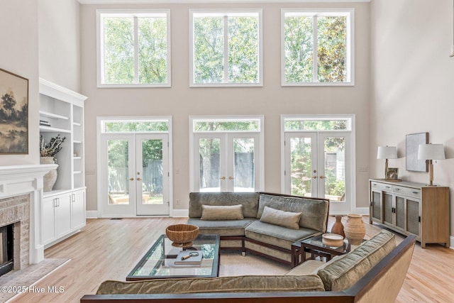 6932 Runningbrook Ter, Wilmington, NC 28411 - living room featuring french doors, a high ceiling, a fireplace with flush hearth, and light wood-style flooring