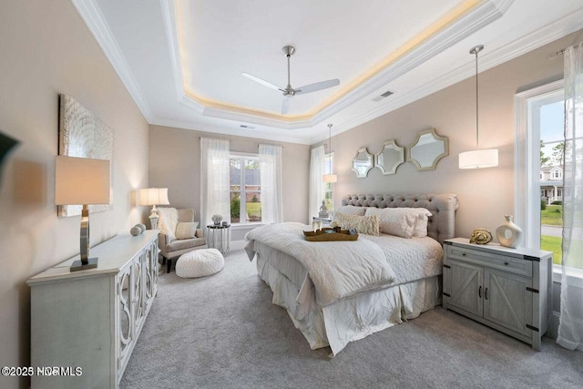 bedroom with a raised ceiling, light colored carpet, ceiling fan, and ornamental molding