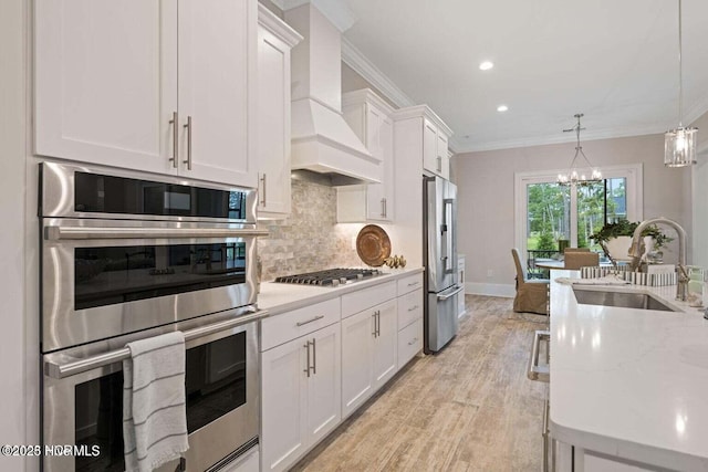 kitchen featuring custom exhaust hood, appliances with stainless steel finishes, a sink, and white cabinets