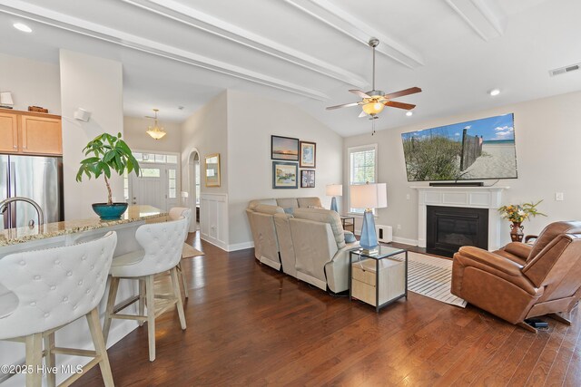 living area with visible vents, ceiling fan, dark wood finished floors, a fireplace with flush hearth, and lofted ceiling