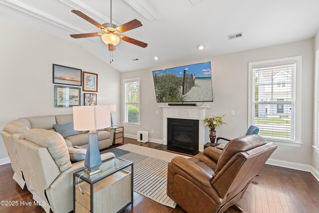 living room with dark wood finished floors, a fireplace with flush hearth, a ceiling fan, vaulted ceiling, and visible vents