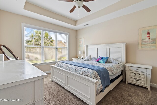 bedroom with a tray ceiling, ceiling fan, baseboards, and carpet