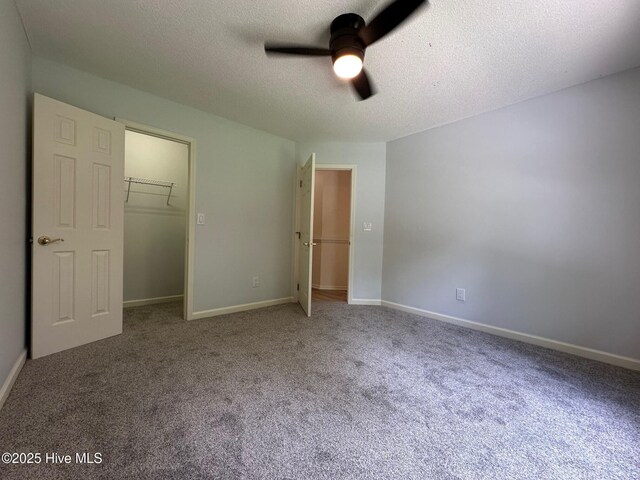 146 Olde Point Rd, Hampstead, NC 28443 - unfurnished bedroom featuring a textured ceiling, carpet flooring, a closet, a ceiling fan, and a walk in closet