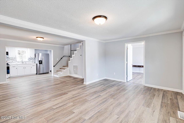 304 N Saratoga St, Stantonsburg, NC 27883 - unfurnished living room with stairs, light wood-style flooring, baseboards, crown molding, and a textured ceiling