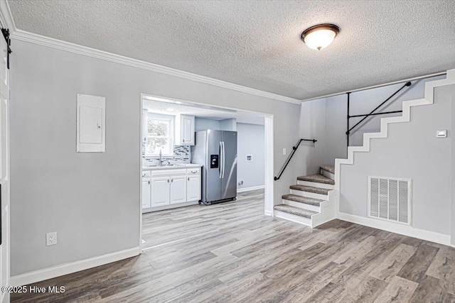 304 N Saratoga St, Stantonsburg, NC 27883 - unfurnished living room with a textured ceiling, stairway, light wood-type flooring, a sink, and crown molding