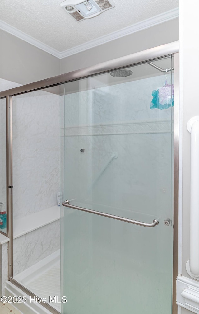 bathroom featuring visible vents, a textured ceiling, a stall shower, and ornamental molding