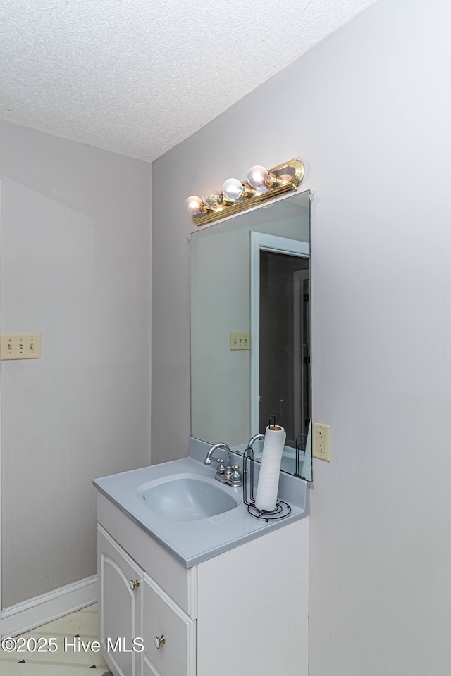bathroom featuring a textured ceiling, vanity, and baseboards