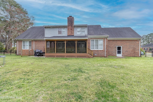 rear view of house with fence, brick siding, a lawn, and a sunroom