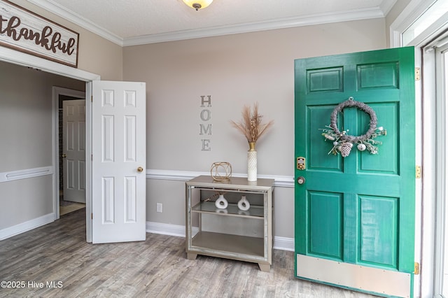 foyer with crown molding, baseboards, and wood finished floors