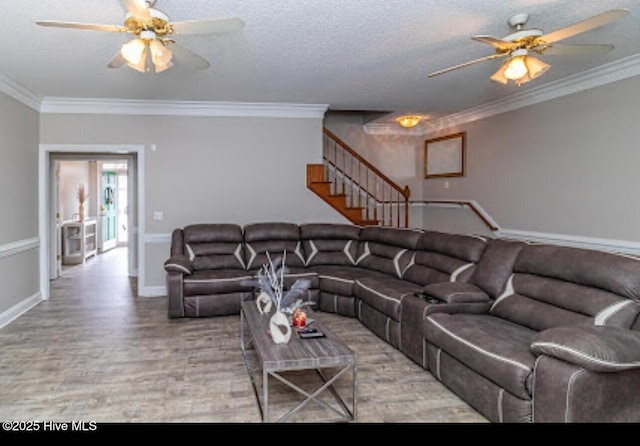 living area with stairs, crown molding, and a ceiling fan