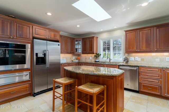 kitchen featuring a skylight, a warming drawer, stainless steel appliances, backsplash, and ornamental molding