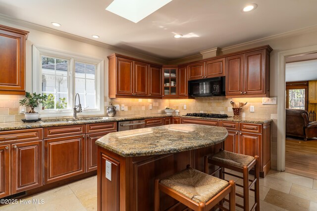 kitchen with a kitchen breakfast bar, a sink, a skylight, black appliances, and ornamental molding