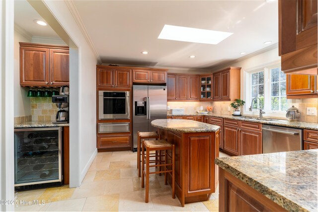 kitchen with a warming drawer, appliances with stainless steel finishes, ornamental molding, and wine cooler