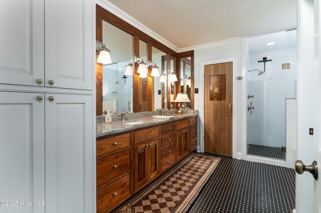 full bath with a sink, a shower stall, double vanity, and crown molding