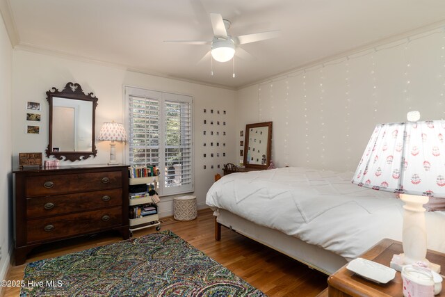 bedroom with wood finished floors, ceiling fan, and ornamental molding