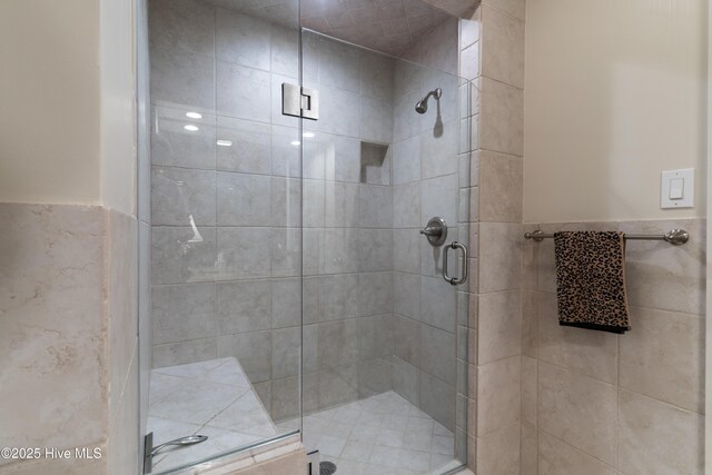 full bath with a shower stall, wainscoting, and tile walls