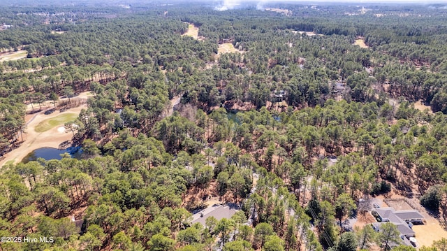 drone / aerial view with golf course view, a forest view, and a water view