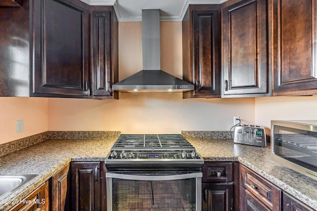 kitchen with stainless steel appliances, dark brown cabinets, crown molding, and wall chimney range hood