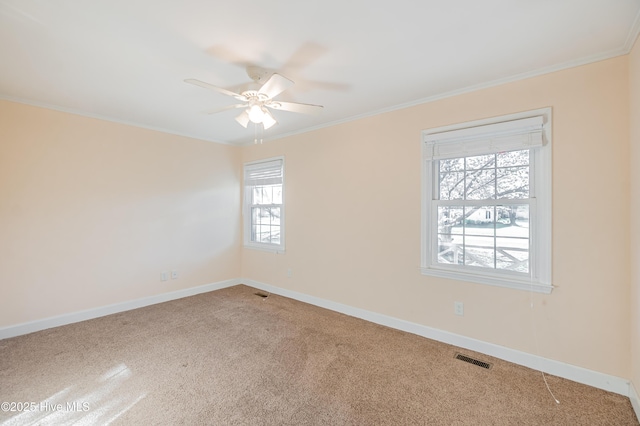 carpeted empty room featuring visible vents, baseboards, ceiling fan, and ornamental molding