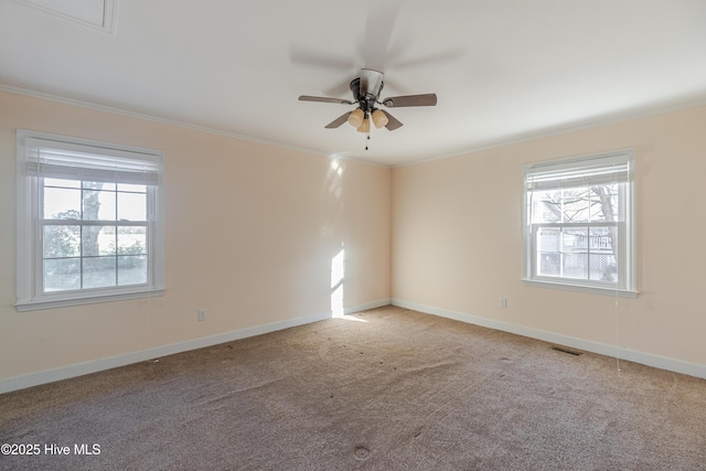 carpeted empty room with visible vents, a healthy amount of sunlight, and ornamental molding