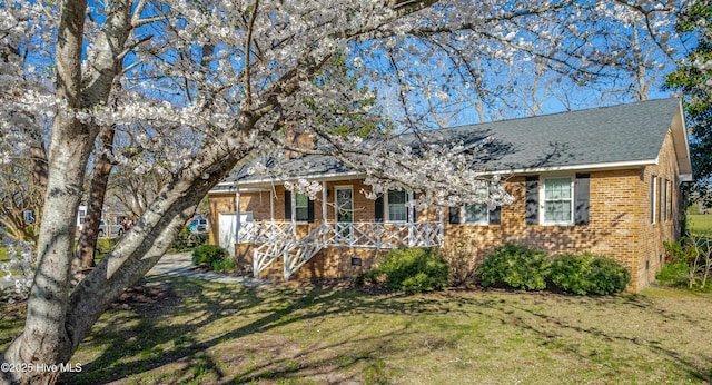 single story home featuring crawl space, brick siding, covered porch, and a front yard