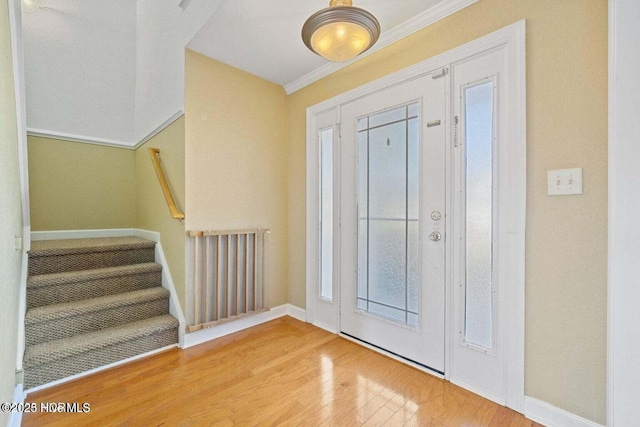 foyer with baseboards, wood finished floors, stairs, and ornamental molding
