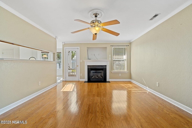 unfurnished living room featuring light wood finished floors, a fireplace with flush hearth, crown molding, and a ceiling fan