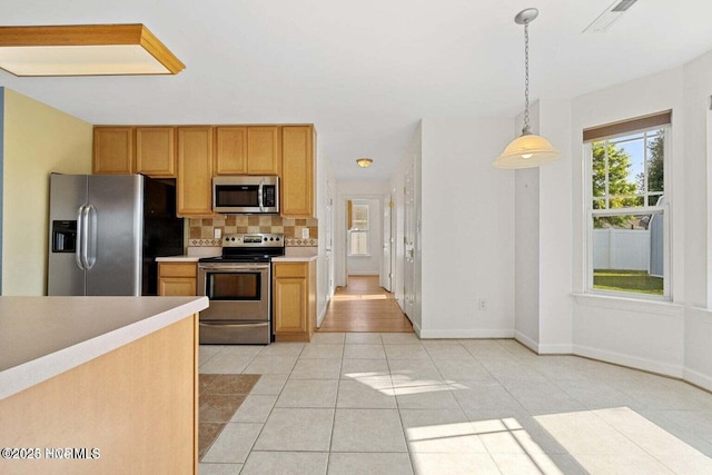 kitchen featuring decorative light fixtures, stainless steel appliances, light countertops, light tile patterned floors, and decorative backsplash