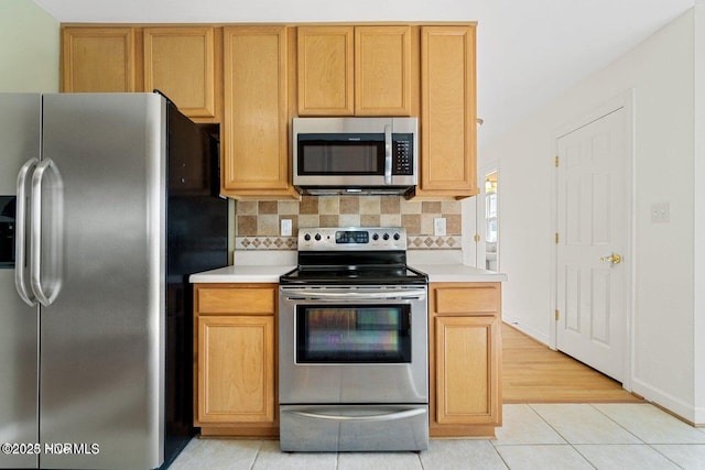 kitchen with light tile patterned floors, tasteful backsplash, appliances with stainless steel finishes, and light countertops