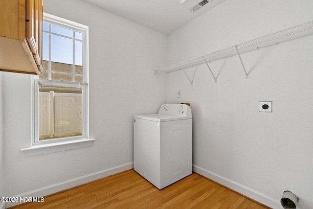 clothes washing area featuring washer / clothes dryer, baseboards, visible vents, and light wood-type flooring