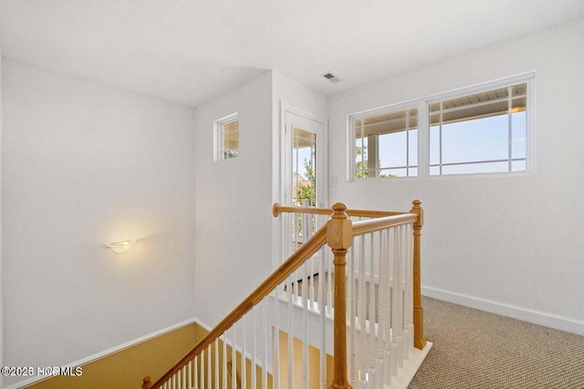 corridor with carpet flooring, an upstairs landing, visible vents, and baseboards