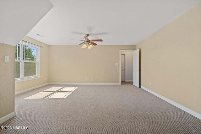 spare room featuring visible vents, light colored carpet, baseboards, and ceiling fan
