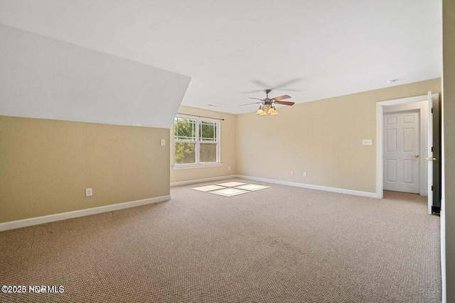 carpeted spare room featuring lofted ceiling, a ceiling fan, and baseboards