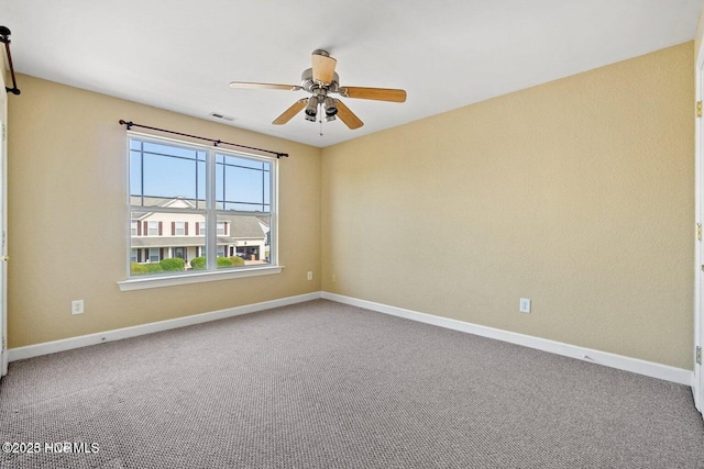 carpeted spare room with visible vents, baseboards, and ceiling fan