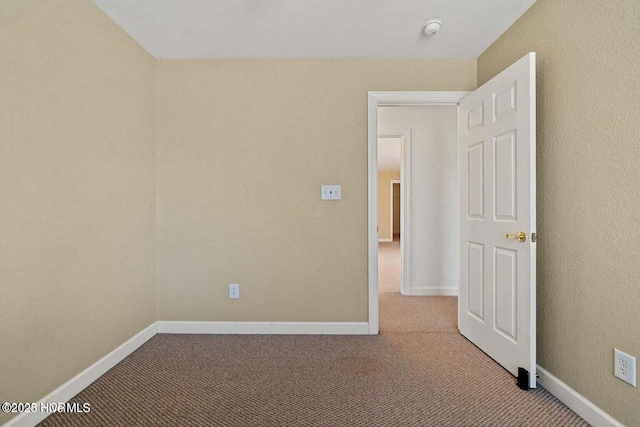 spare room featuring light carpet and baseboards