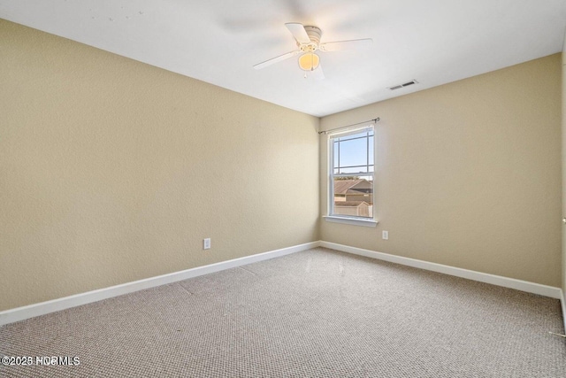 carpeted spare room with visible vents, baseboards, and a ceiling fan