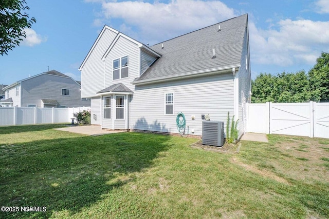 rear view of house with a patio area, central air condition unit, a fenced backyard, and a yard
