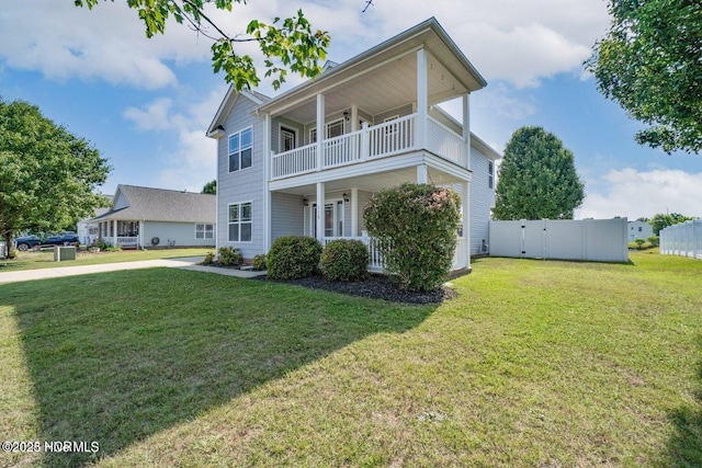 view of front of property featuring a balcony, a front yard, and fence