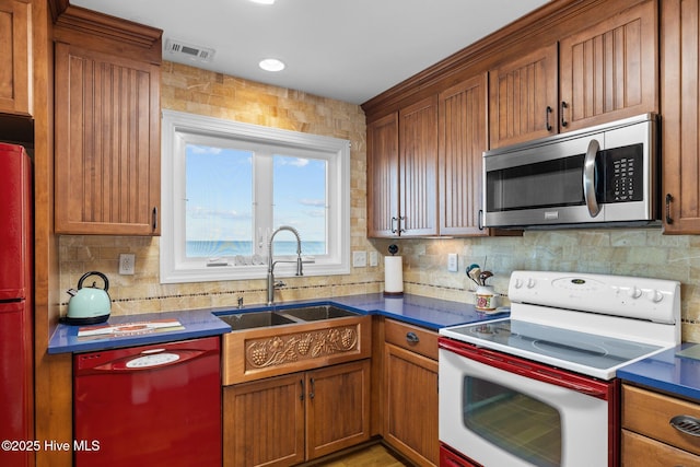 kitchen with a sink, dishwasher, stainless steel microwave, dark countertops, and electric range