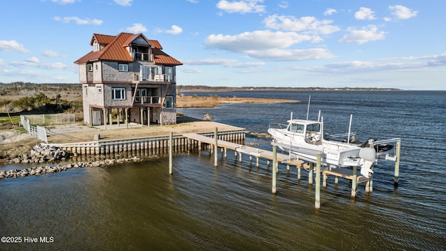 dock area with boat lift, a balcony, and a water view