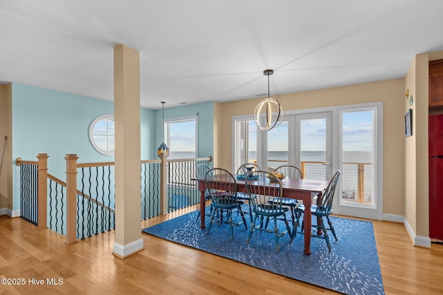 dining area featuring baseboards, a water view, and light wood-style floors