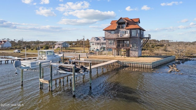 dock area with a balcony, a water view, and boat lift