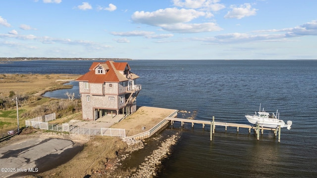 dock area with boat lift, a water view, and fence