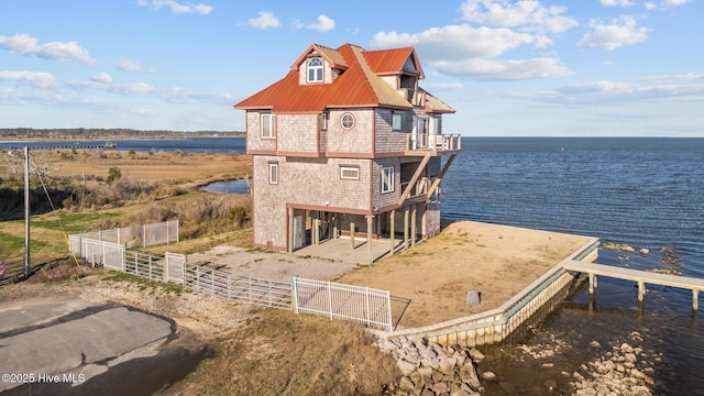 exterior space featuring a balcony, metal roof, a water view, and fence