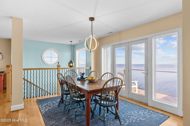 dining room with light wood-style flooring and a water view