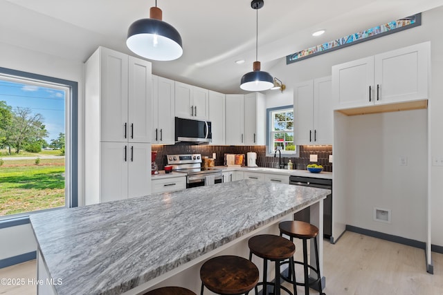 kitchen with decorative backsplash, stainless steel appliances, and white cabinets