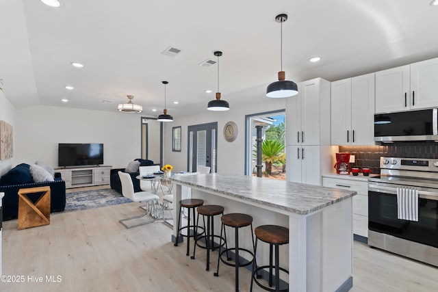 kitchen with open floor plan, appliances with stainless steel finishes, tasteful backsplash, and light wood finished floors