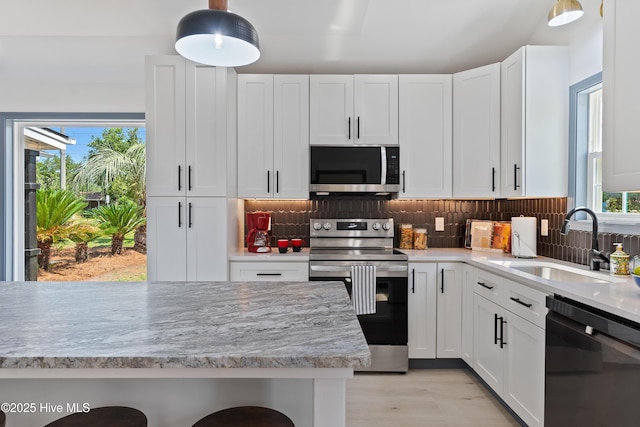 kitchen with stainless steel appliances, light countertops, a sink, and white cabinetry